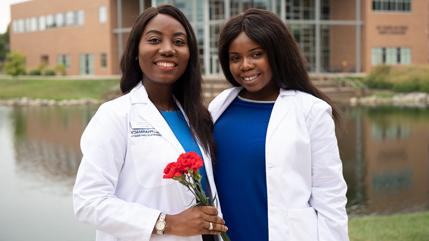 2019年，沙巴体育药学专业的学生Gloria Aboagye(左)和Abena Mpere(右)庆祝获得白大褂