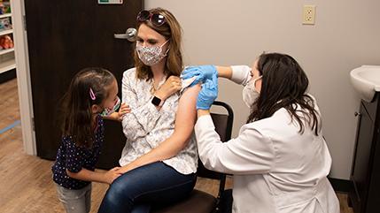 药剂师在小女孩的注视下给病人注射疫苗