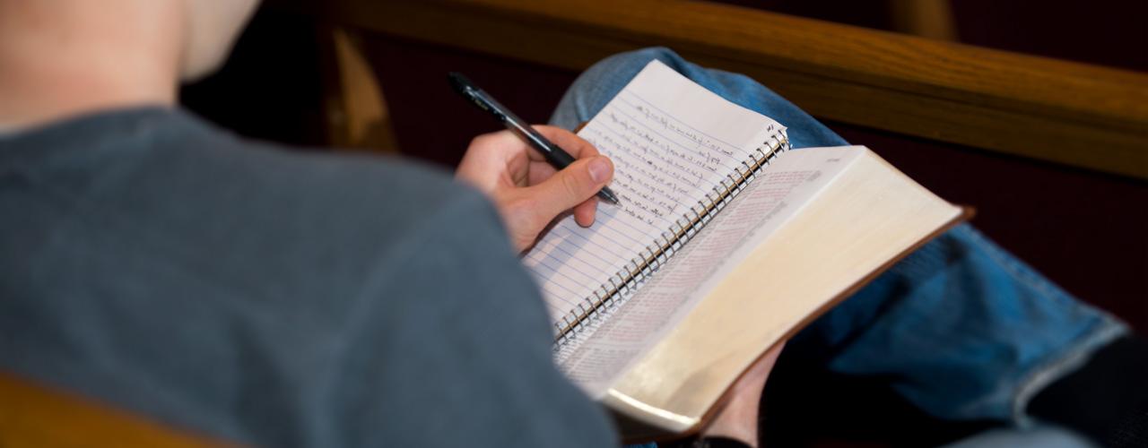 A student takes notes during chapel